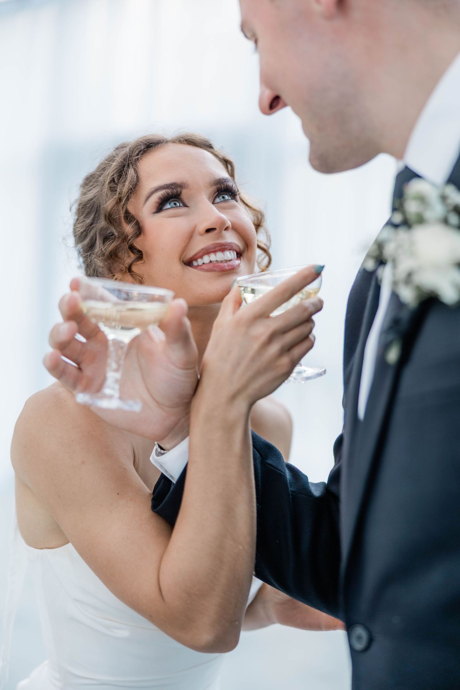 Bride and groom share romantic moment while holding champagne glasses at wedding reception.