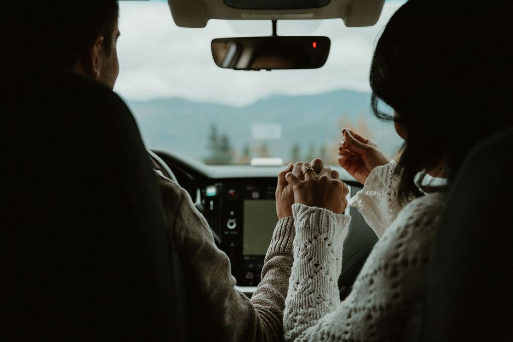 Silhouetted figures in car against mountain landscape.
