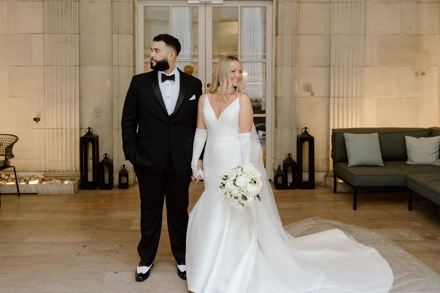 A formal wedding couple standing in an elegant venue with classic architectural details.