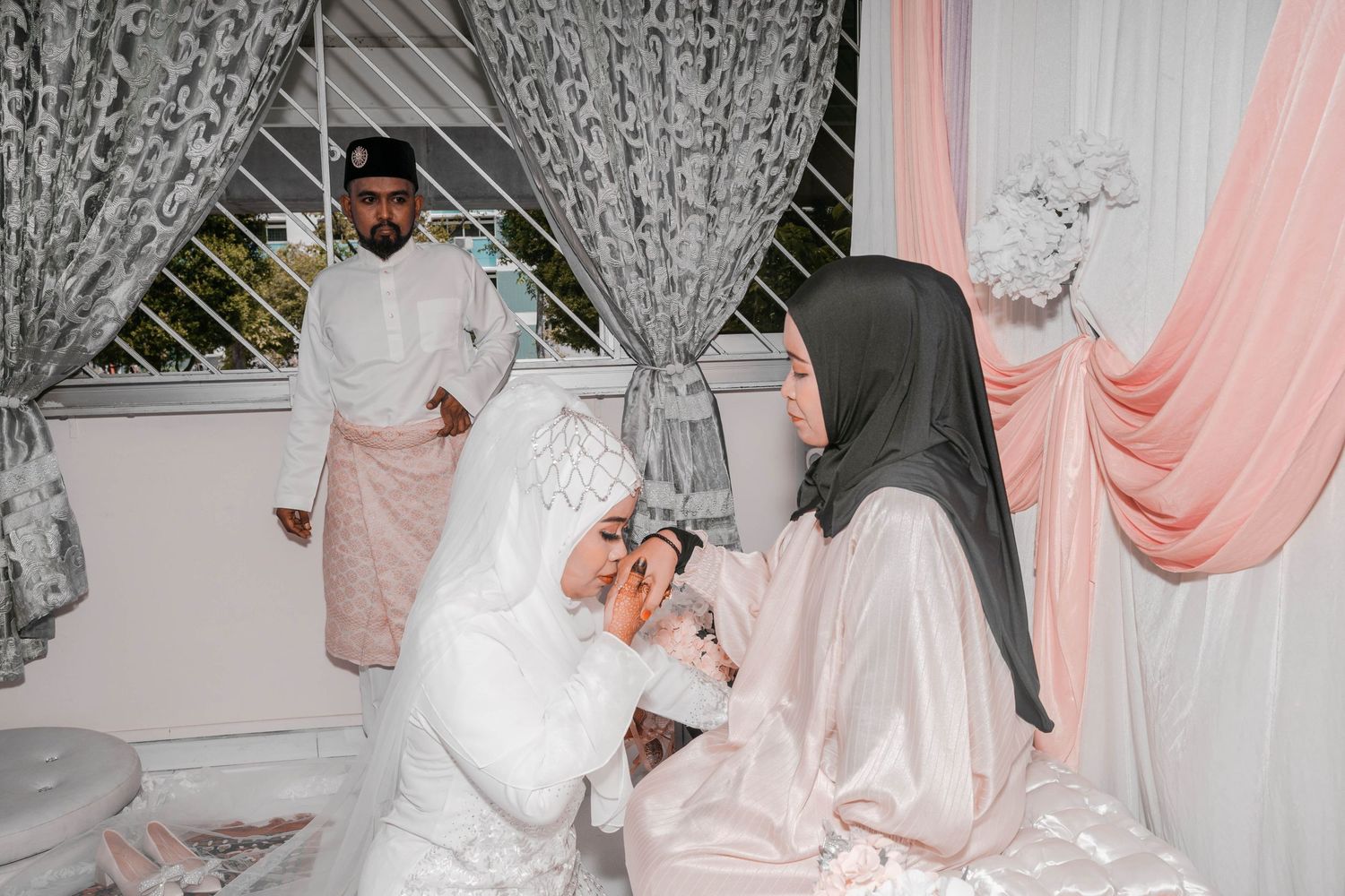 Wedding ceremony participants gathered in a decorated room with white and pink drapery.