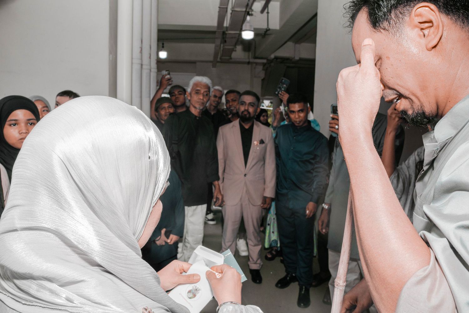 Emotional wedding ceremony moment captured with guests watching signing of marriage documents.