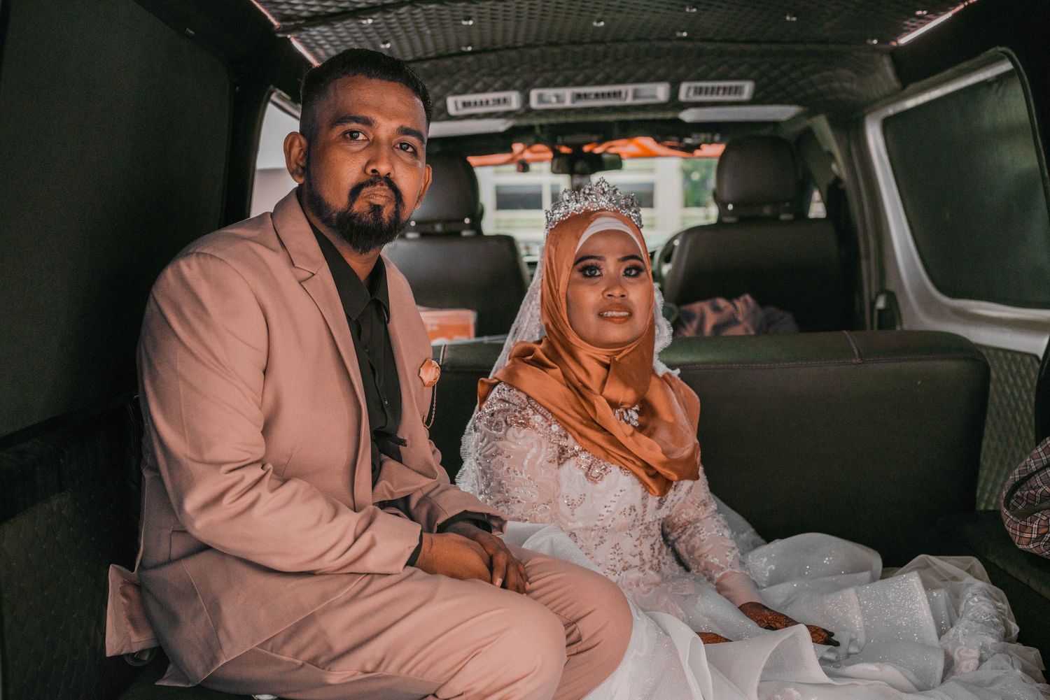 Newlyweds seated together in car after wedding ceremony.