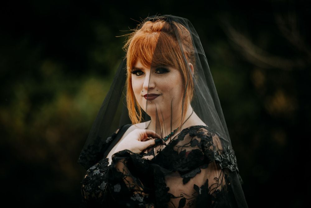 A bridal portrait showcasing a gothic-inspired black lace wedding dress and dramatic veil.