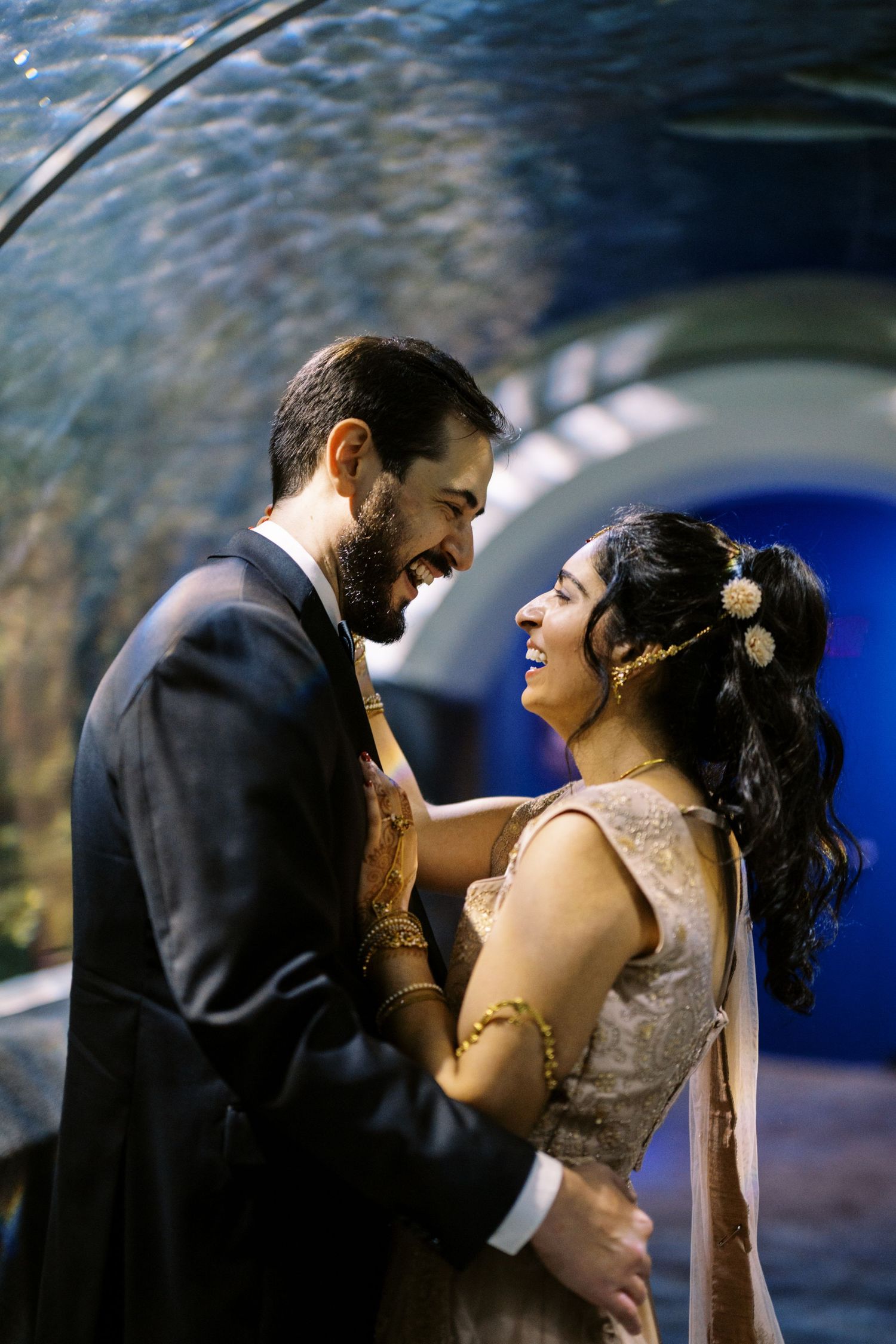 A joyful couple shares a romantic moment while standing in front of a blue aquarium backdrop.
