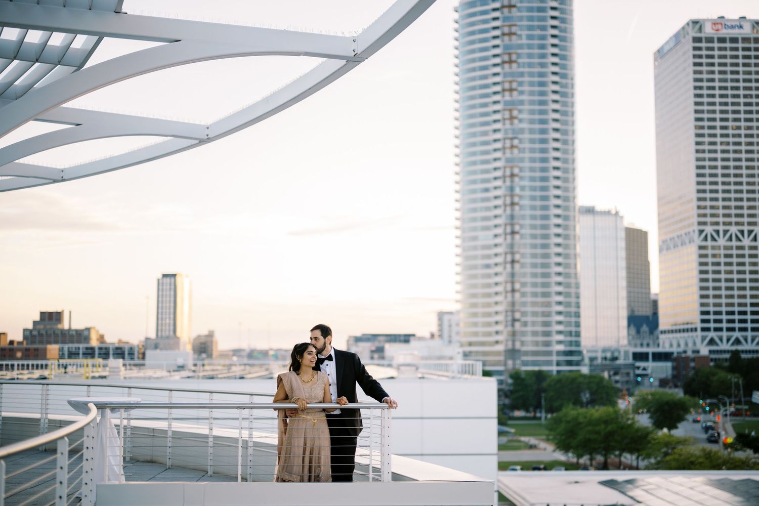A couple enjoys a romantic moment on a modern urban rooftop with tall skyscrapers and city views in the background.