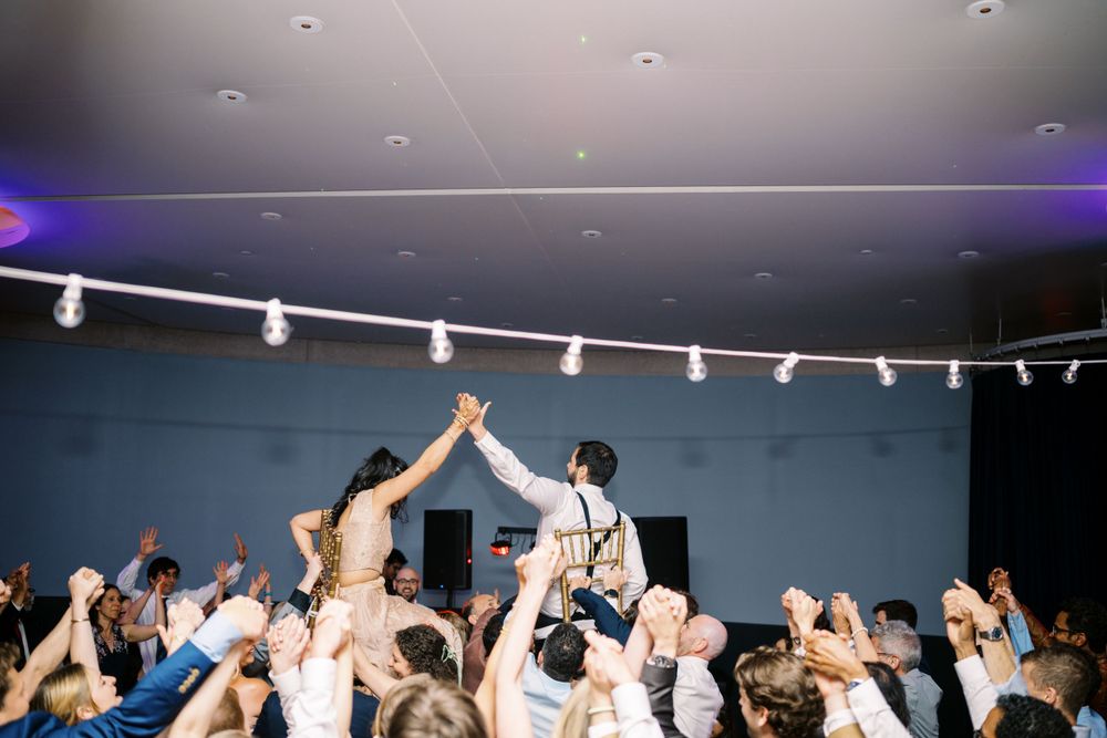 A celebratory moment at a reception as a couple raises their joined hands above a cheering crowd.