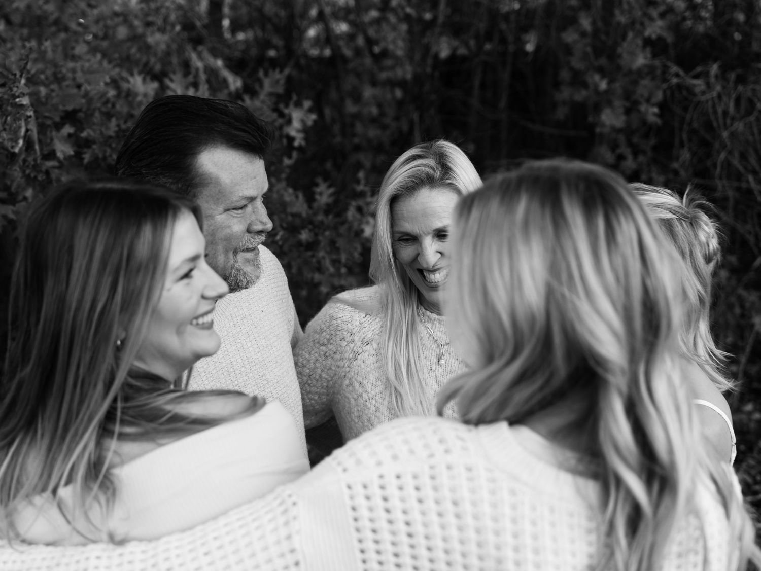 Group of friends in white sweaters sharing a candid moment outdoors.