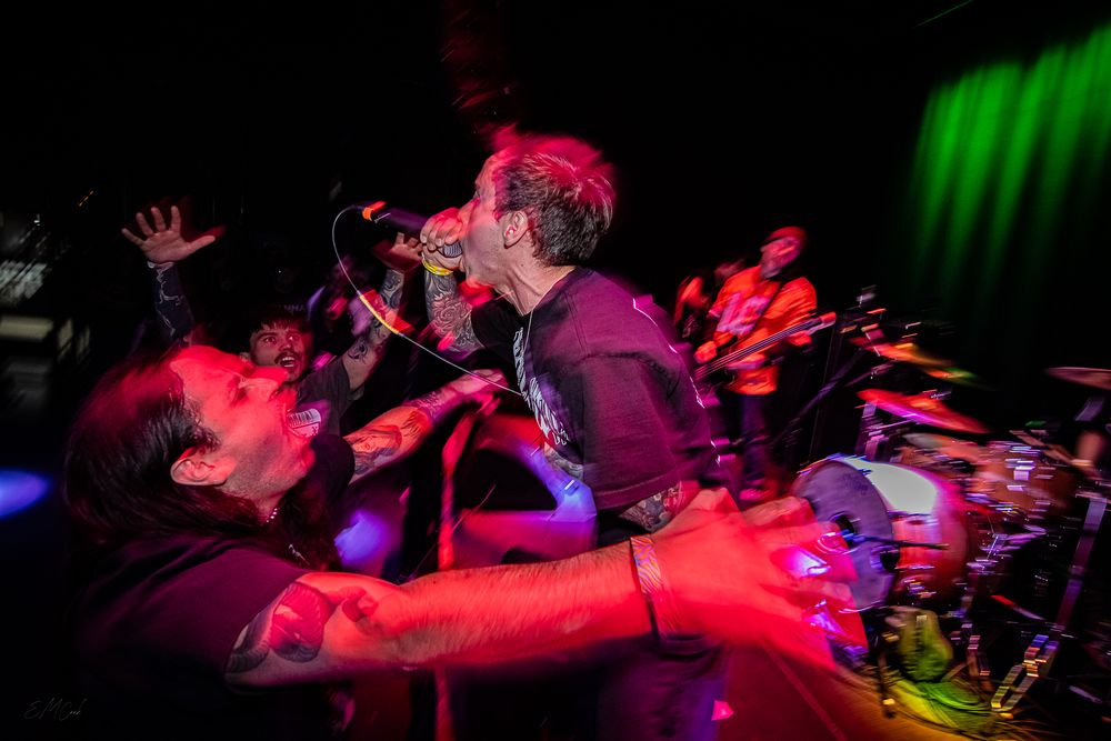 Energetic concert performance captured in motion blur with dramatic red and green stage lighting.