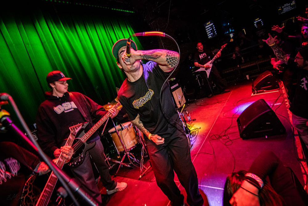 Energetic live music performance on stage with dramatic red and green lighting effects.