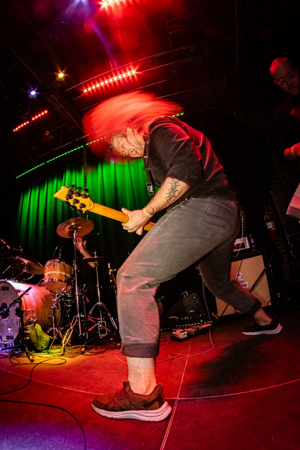 Low angle shot of performers on stage with vibrant red and green stage lighting.