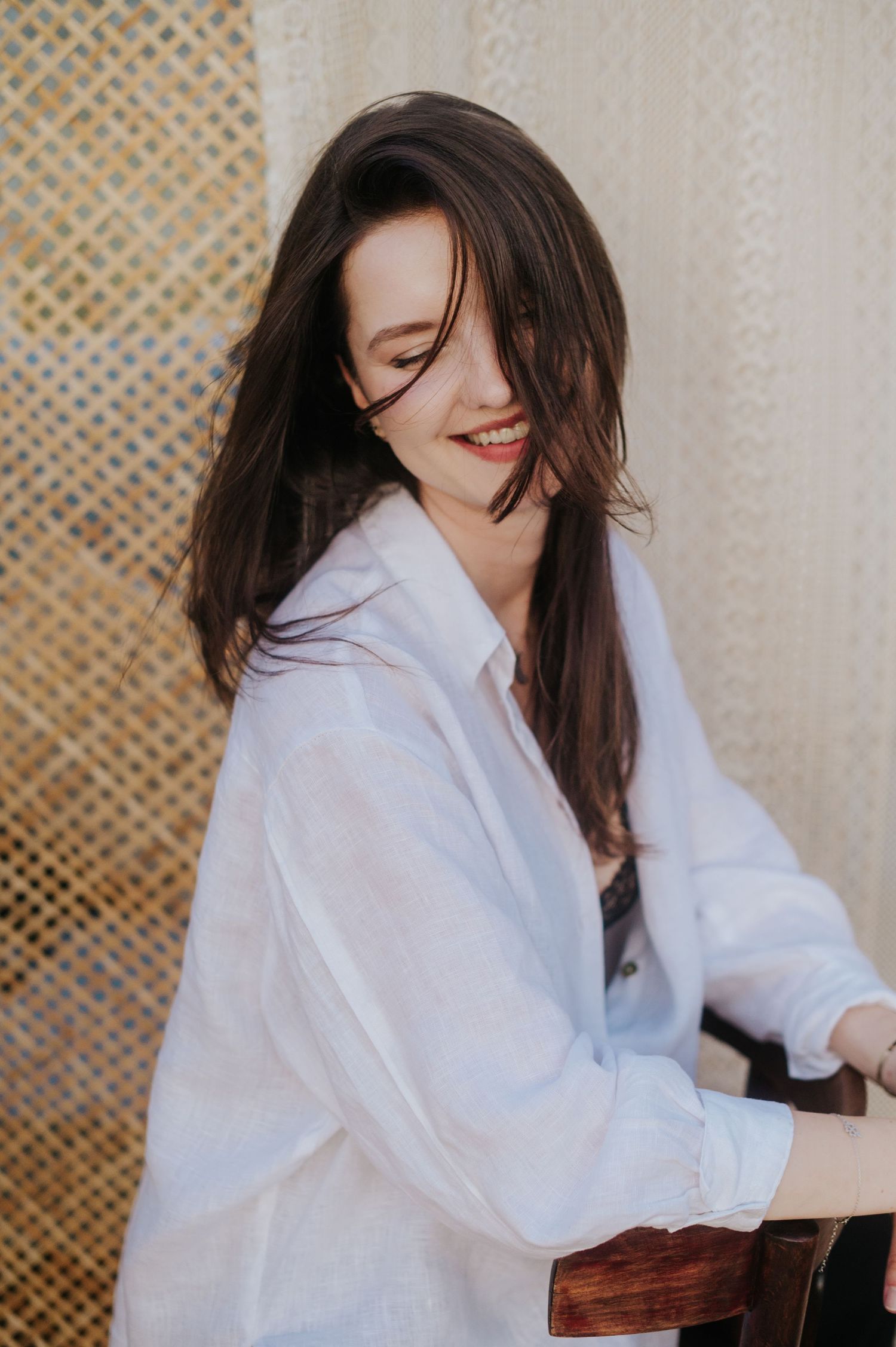 Person in white button-down shirt poses against a lattice backdrop in a series of artistic portraits.