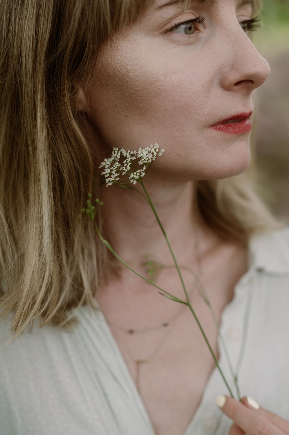 Portrait series showing delicate white flowers held against a soft natural background in ethereal lighting.