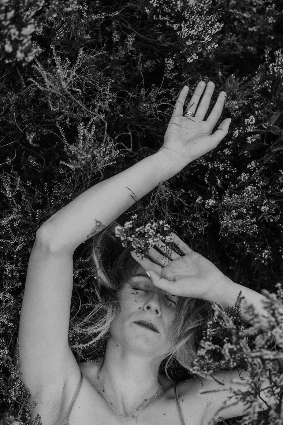 Black and white artistic portrait series showing upturned faces with raised arms against foliage in dramatic poses.
