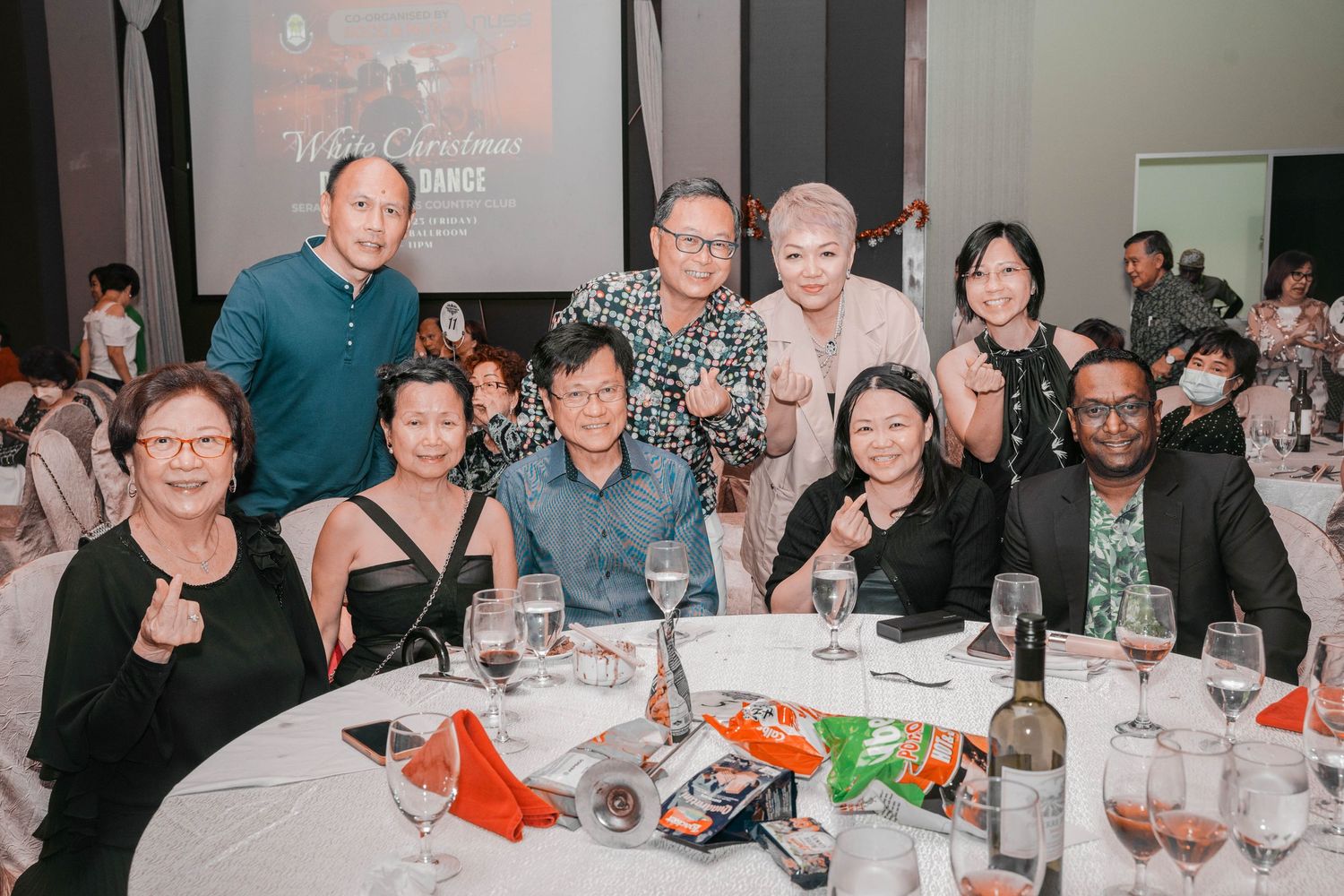 Guests gathered around a round dining table at a formal event with drinks and snacks.