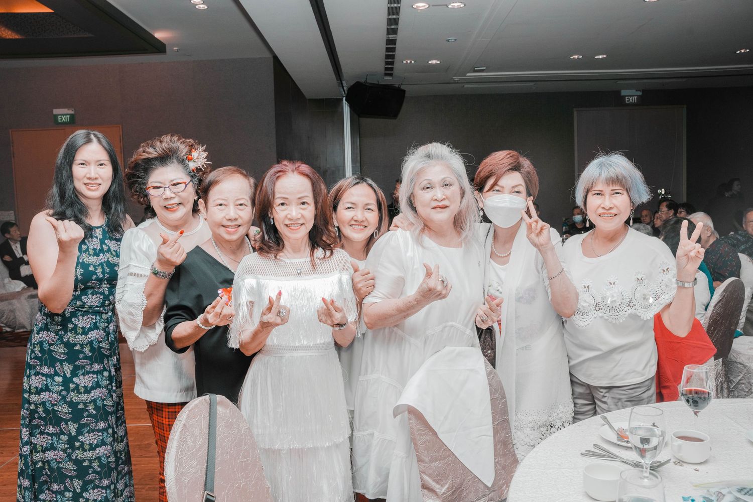 A group of women in white and formal attire posing together at a celebratory event.