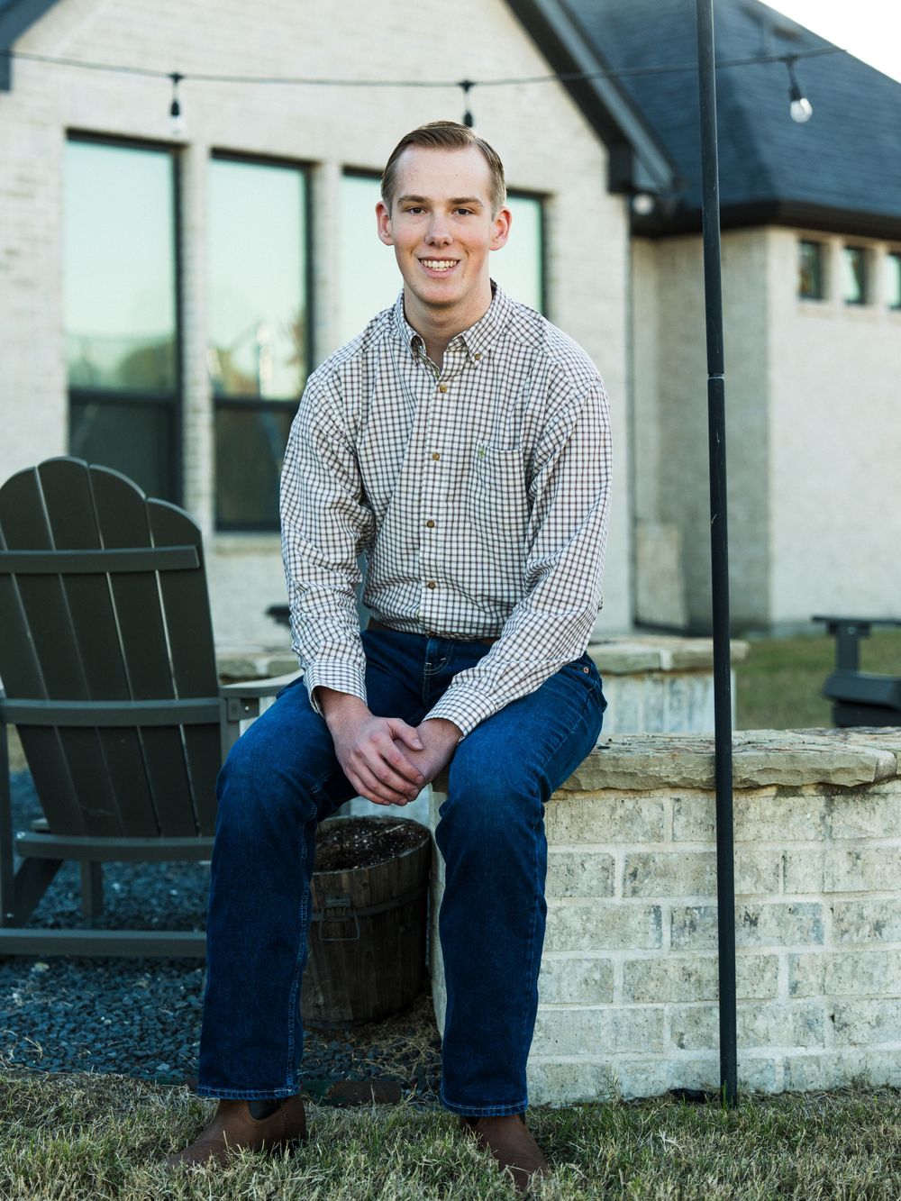Person in plaid button-down shirt sitting on outdoor patio furniture.