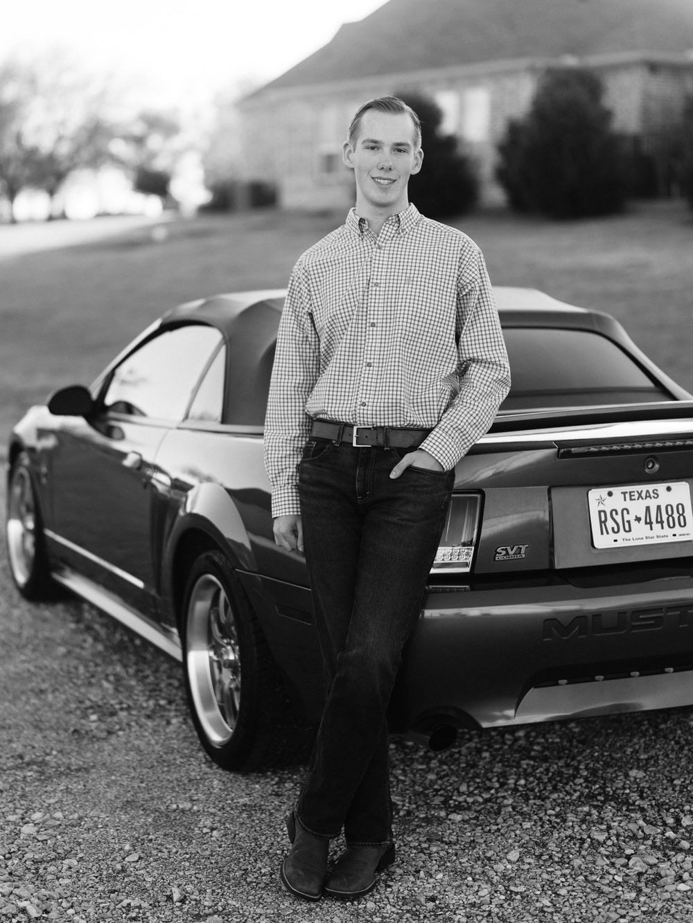 Classic green Mustang with Texas license plate parked on gravel driveway.