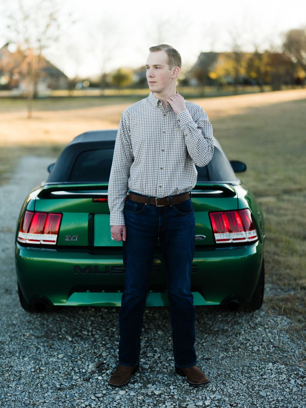 Green Mustang with distinctive taillights parked on gravel lot at dusk.