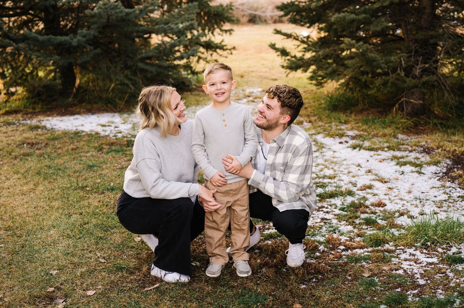 Candid family moment captured in a snowy forest setting with everyone wearing neutral colors.