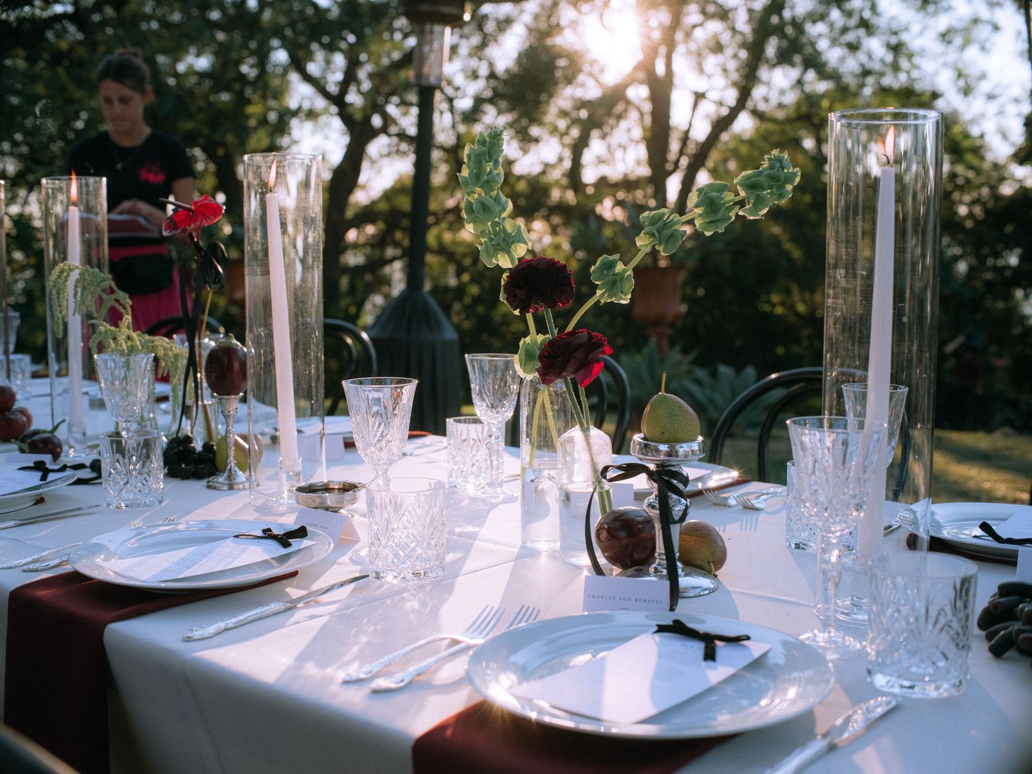 Elegant wedding reception table setting with crystal glasses and floral centerpieces at sunset.