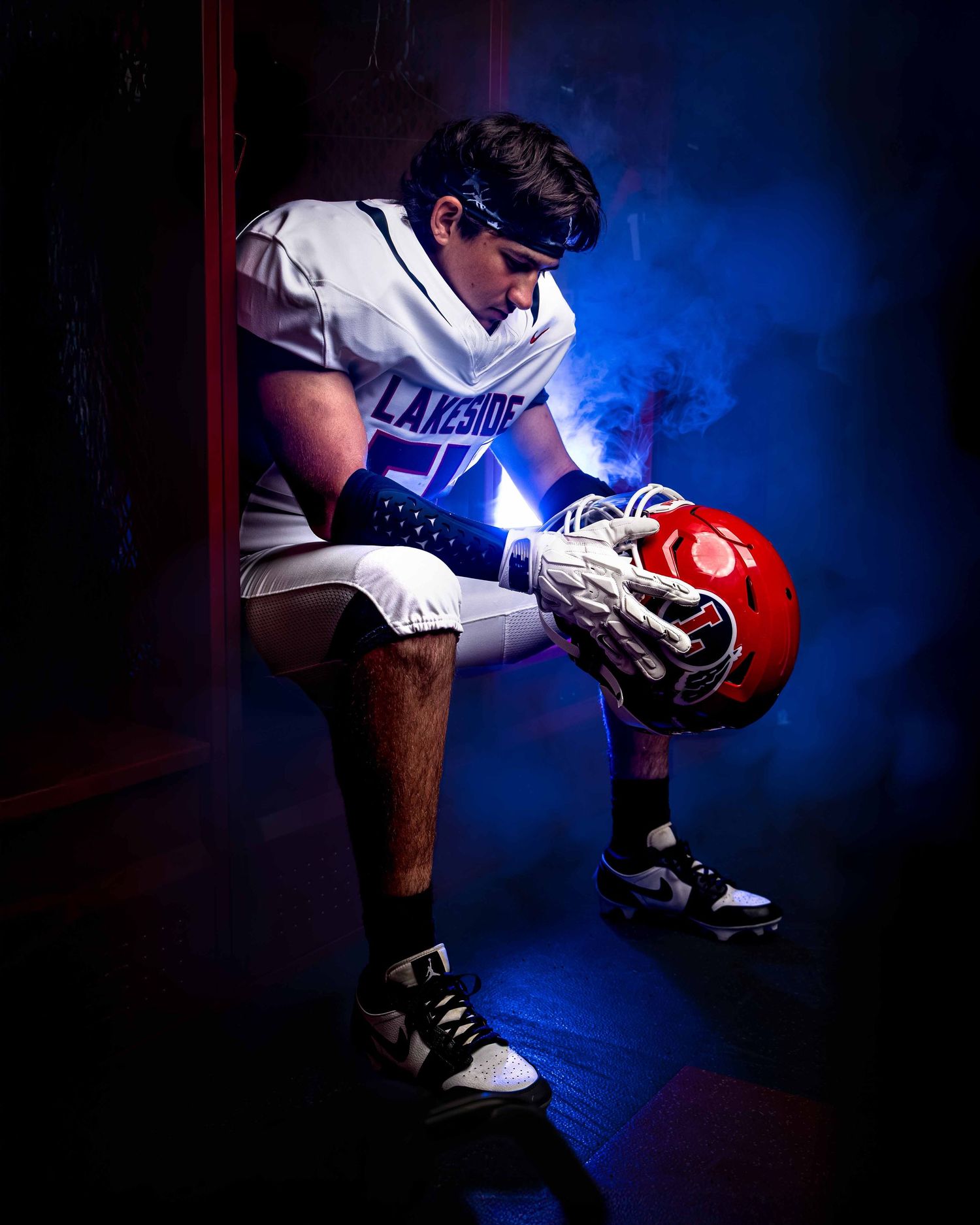 A baseball player in uniform crouches in a dramatic pose against a dark blue background with smoke effects.