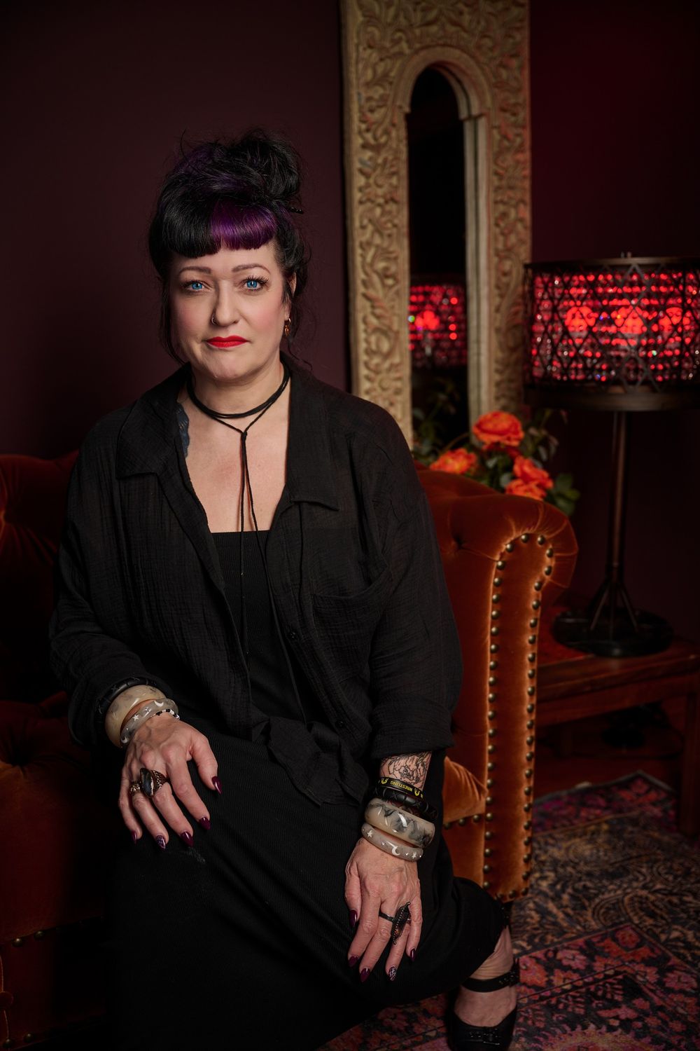 Vintage gothic inspired photoshoot in a dark room with ornate decorative frames and red accent lighting.
