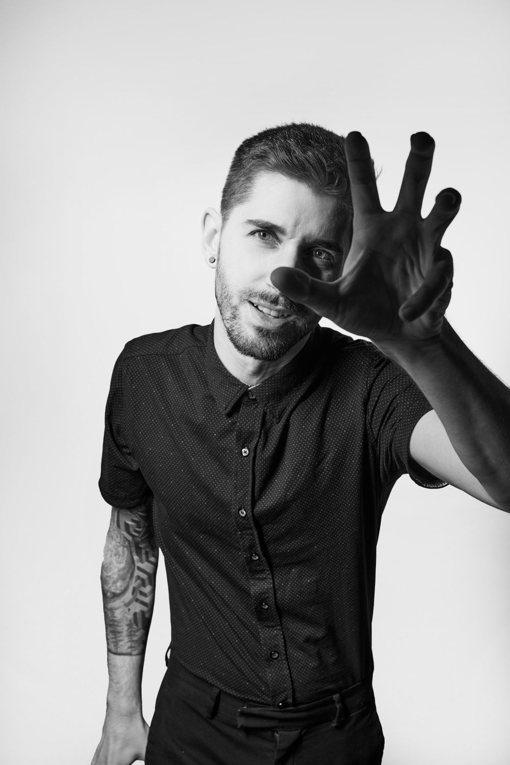 Man in black button-up shirt raising hand in multiple artistic poses against white background.