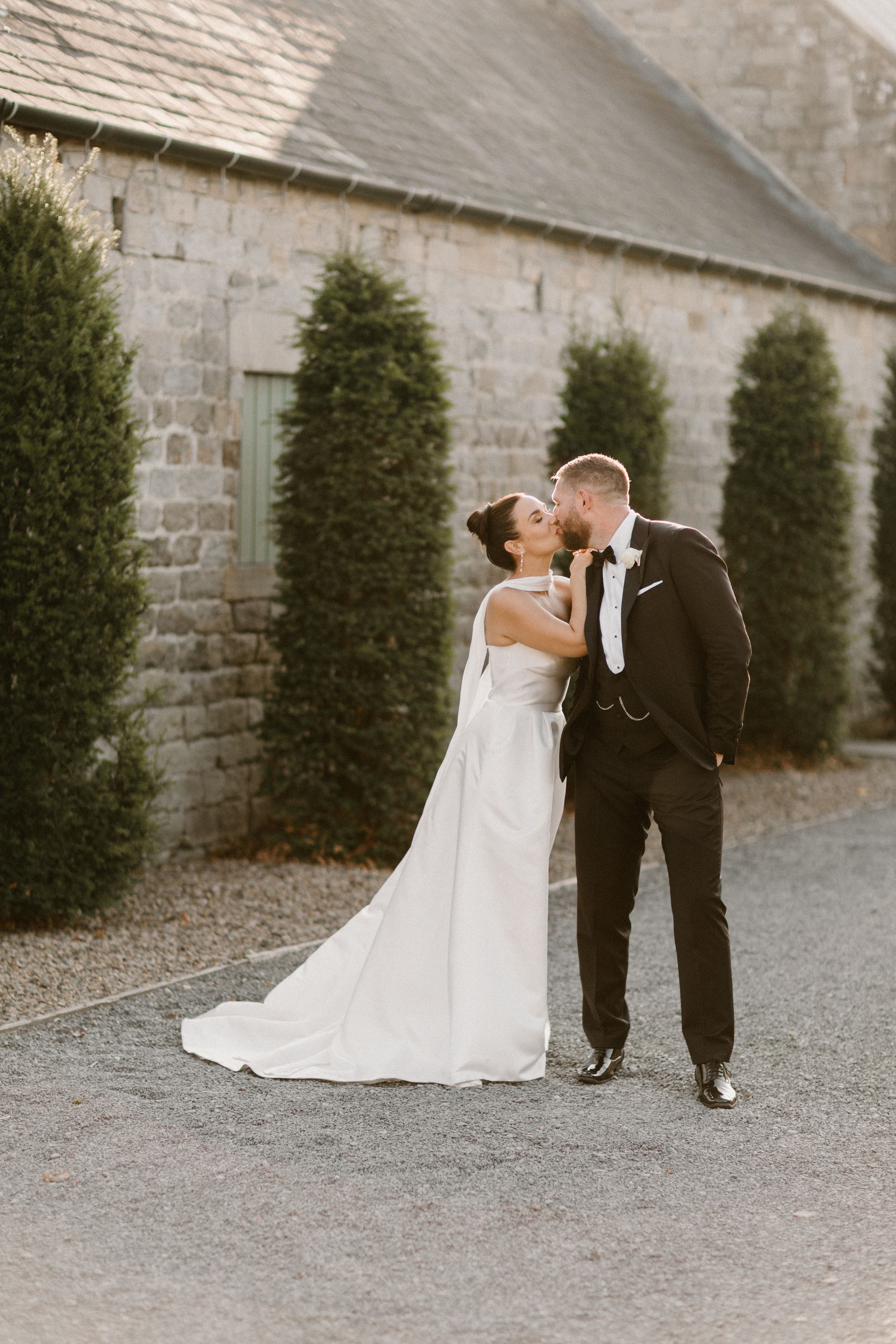 A romantic sequence of wedding photos showing a couple kissing and embracing against a rustic stone wall backdrop.
