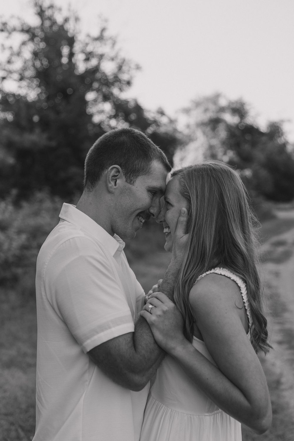 Intimate black and white portrait of a couple sharing a tender moment outdoors.