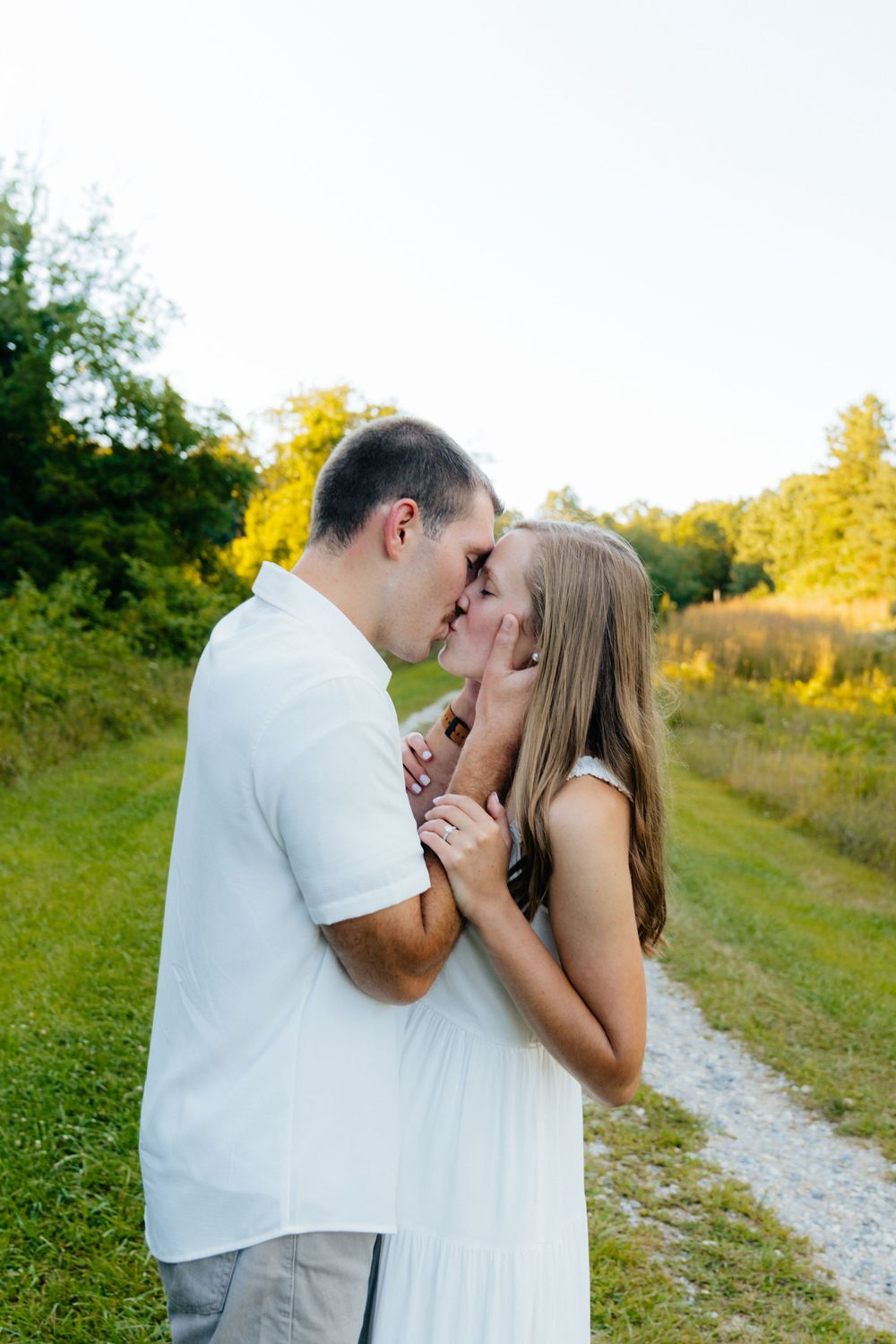 Romantic couple embraces on a sunlit path with golden hour lighting.