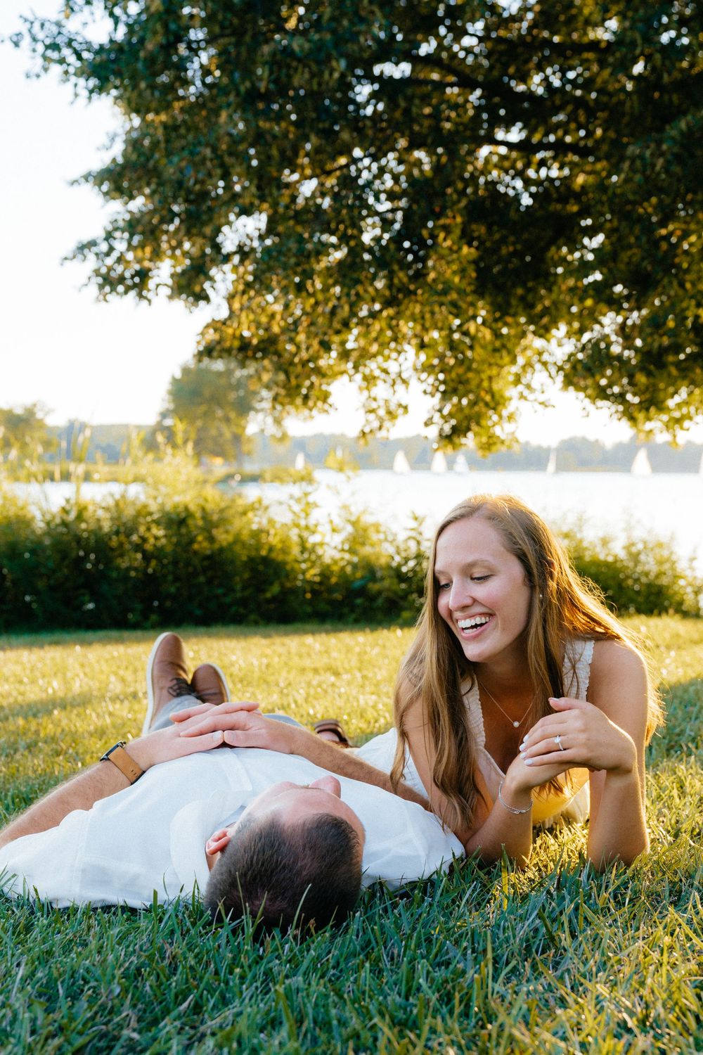 Couple lying in grass during golden hour sunset photoshoot.