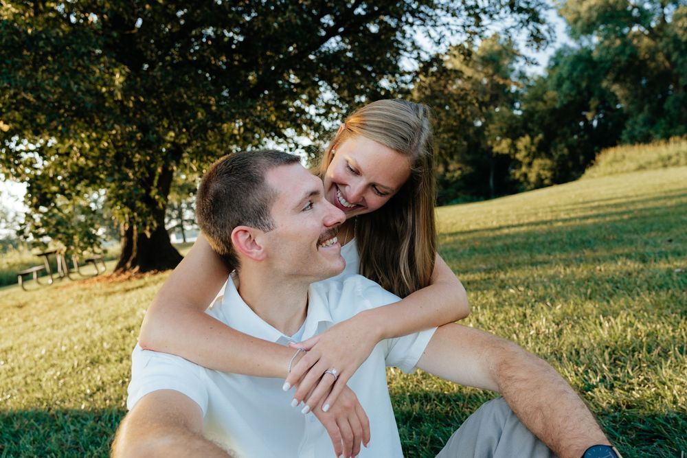 Couple sharing playful moments while lying in grass during sunset.