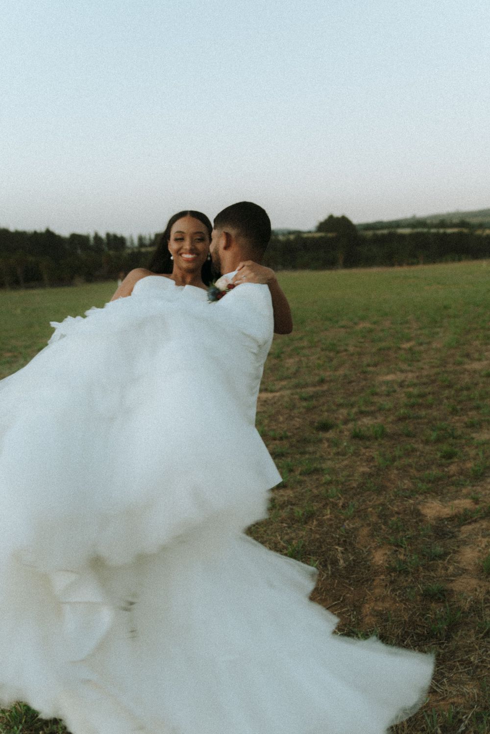 Wedding couple sharing intimate moment in outdoor field setting.
