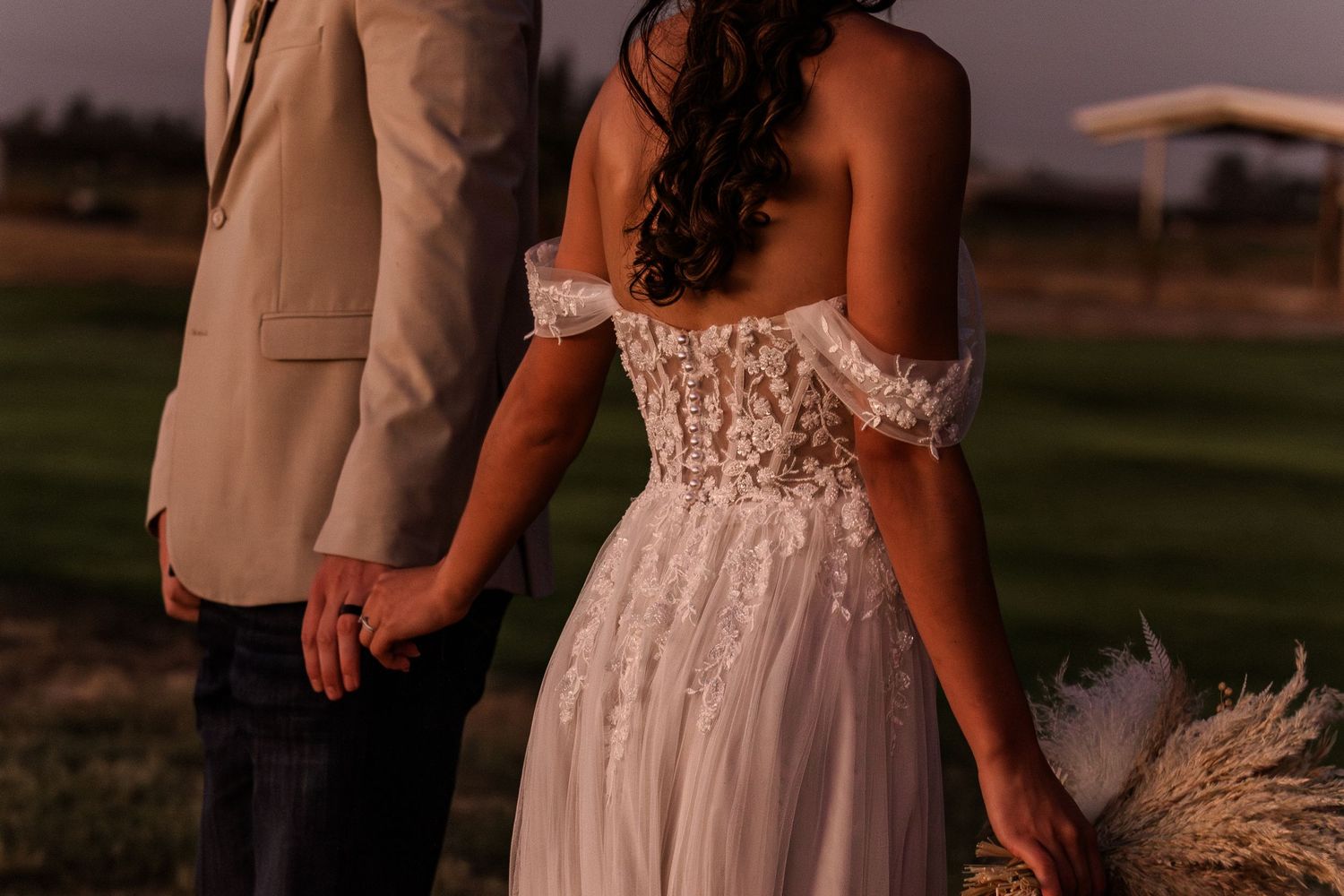Outdoor wedding reception at dusk with romantic lighting and dancing couples.