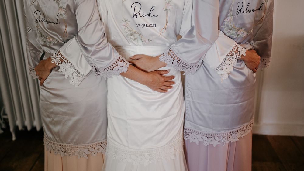 Bride and bridesmaids wearing personalized white robes before wedding ceremony.