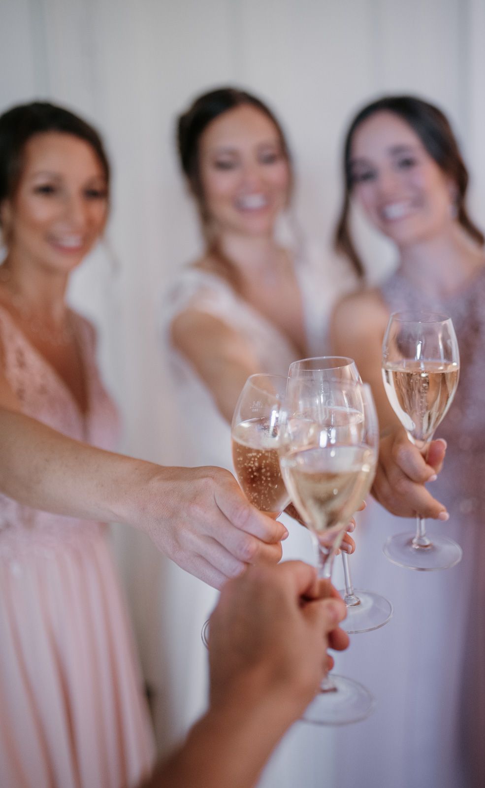 Bride and bridesmaids in pink dresses toasting with champagne glasses.