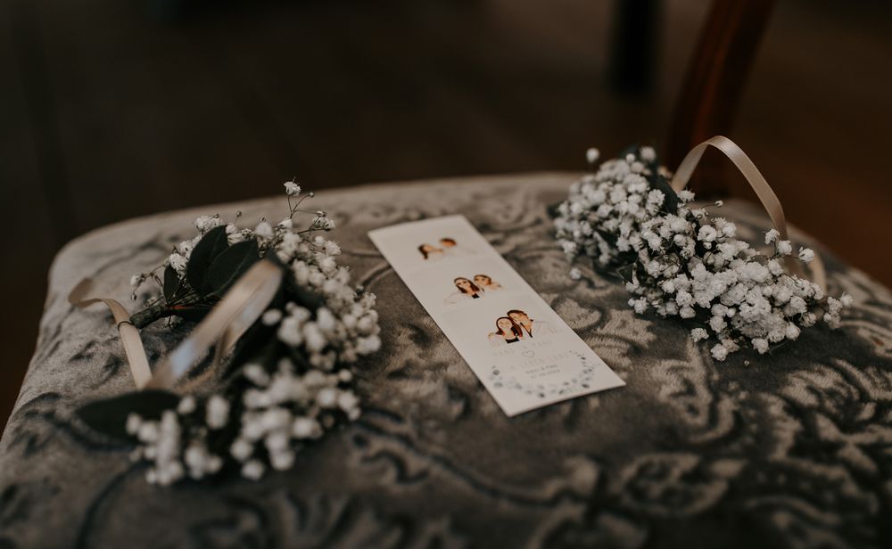 Elegant flat lay of wedding rings, earrings, and baby's breath flowers arranged on a vintage chair.