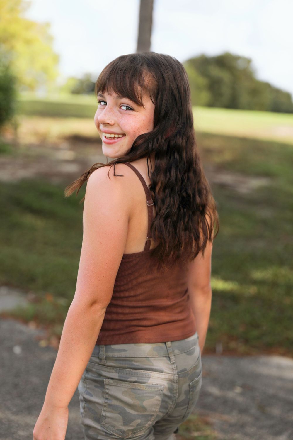 Casual outdoor portrait showing relaxed poses in a brown top and jeans.