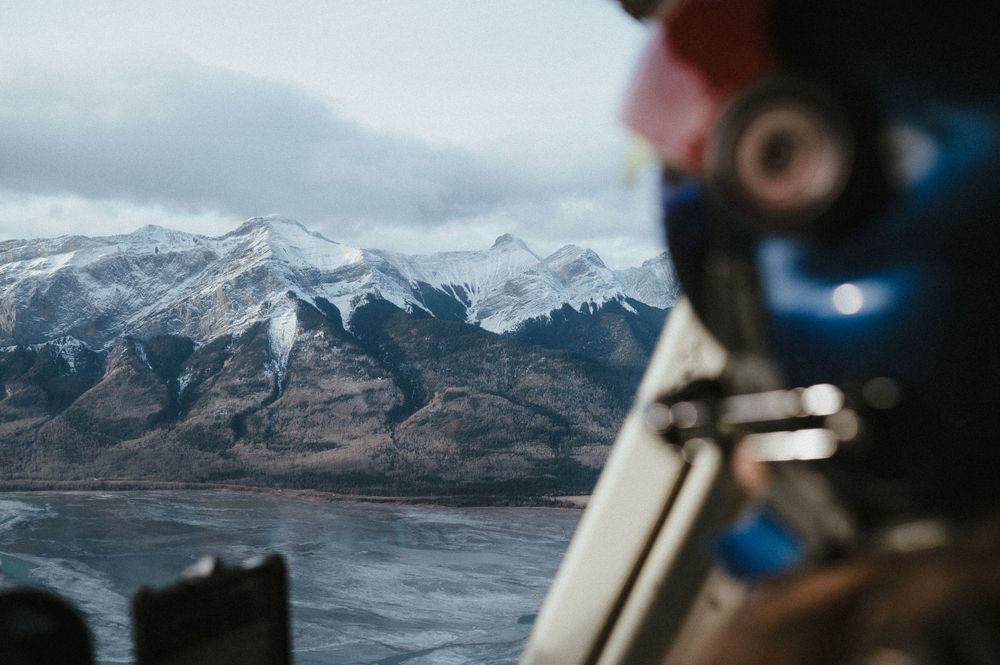 Snow-capped mountain peaks viewed through helicopter window during flight.