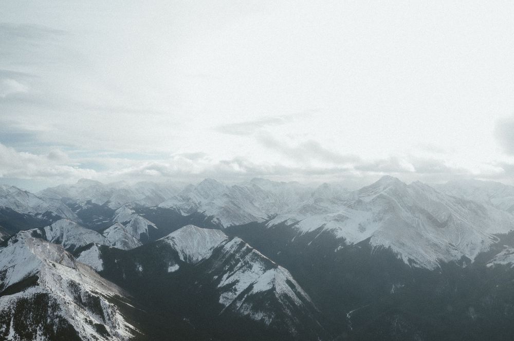 Panoramic view of snow-capped mountain ranges under cloudy winter sky.
