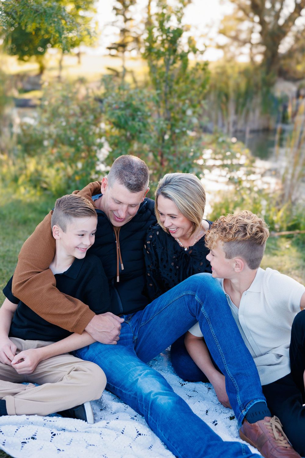 A family sitting together outdoors on a blanket sharing a candid moment during a fall photography session.