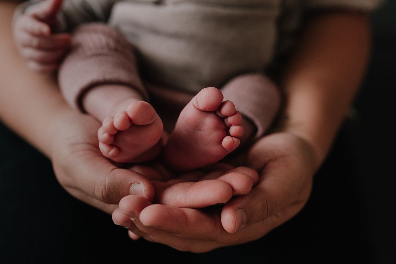Die Hände der Eltern halten die kleinen Füße ihres Babys.