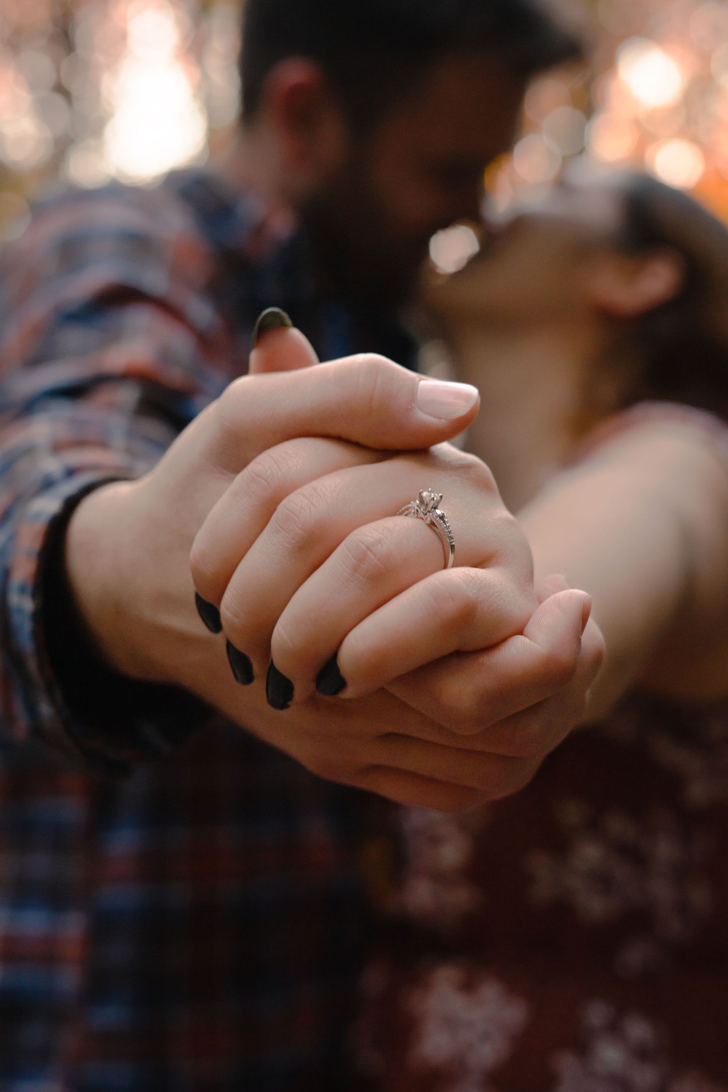 close up of two people holding hands. newly engaged, and showing off the ring moments after saying yes.