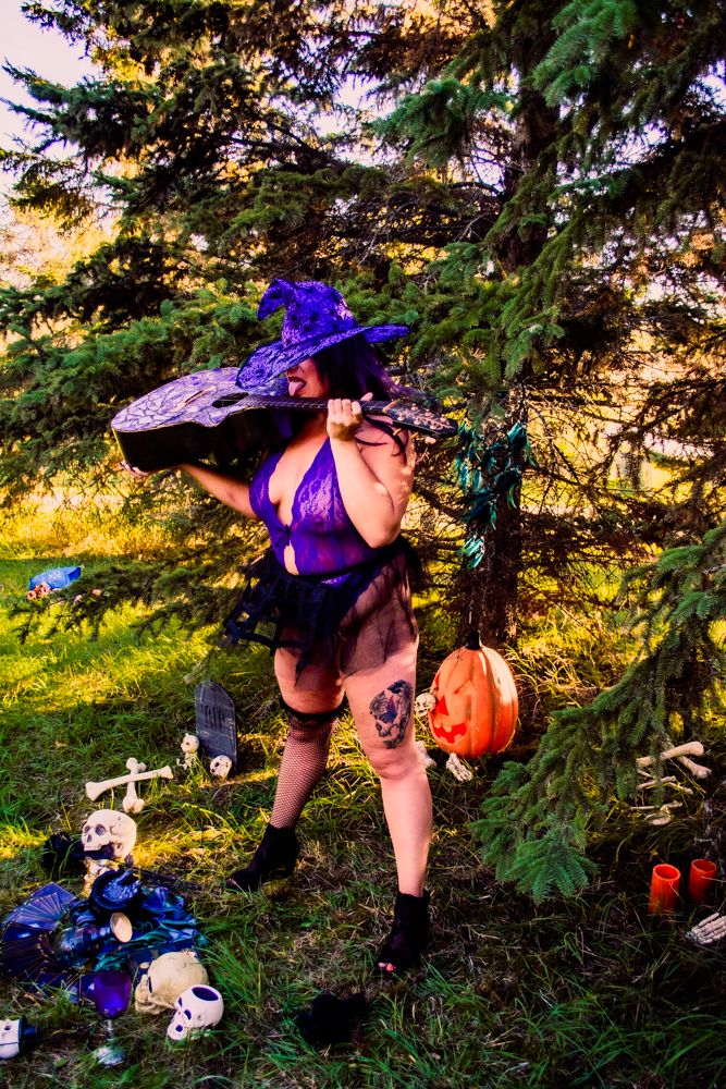 Witch-themed outdoor scene with purple hat, pumpkins and spooky decorations in forest setting.