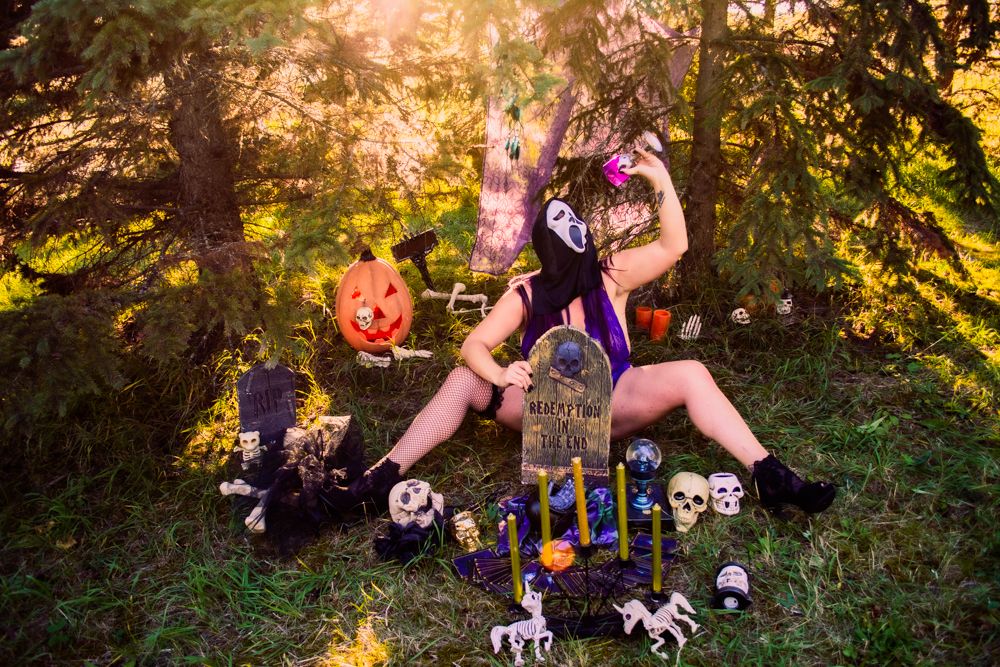 Atmospheric Halloween setup in forest with carved pumpkins, skulls and decorative tombstones.