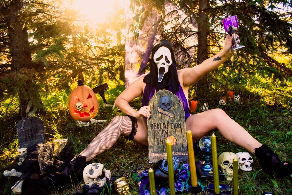 Halloween themed outdoor scene with ghostface mask, cemetery props and orange glowing pumpkins.
