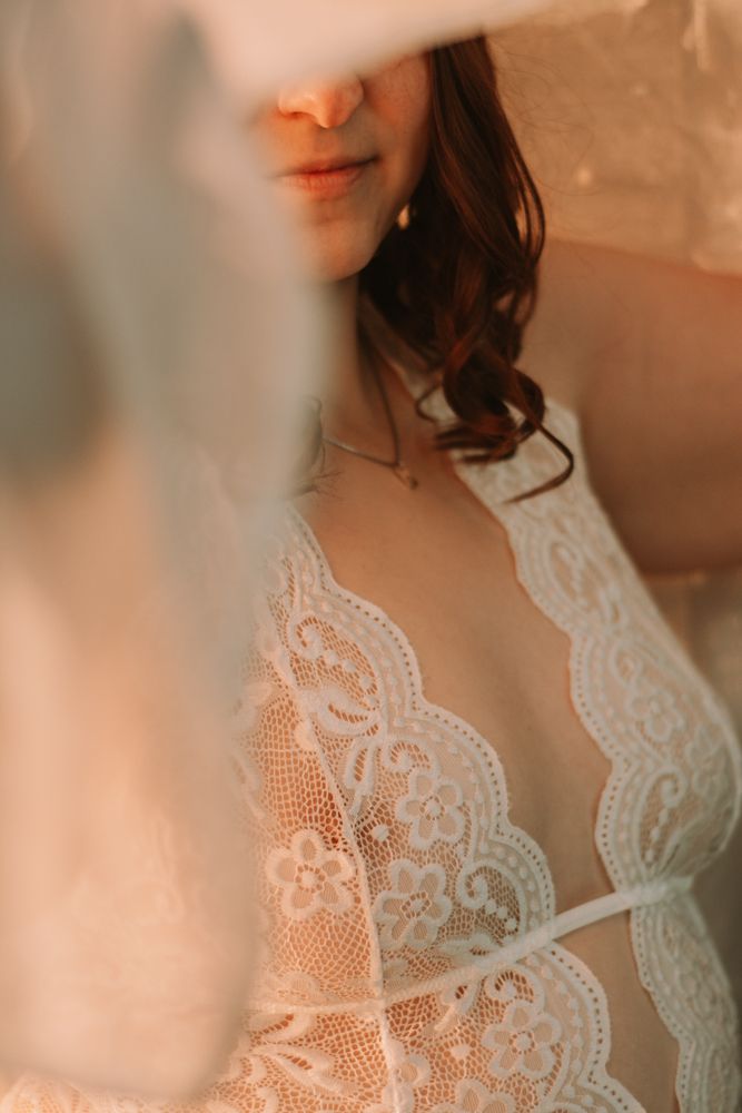 Close-up detail shot of delicate white lace lingerie pattern in warm lighting.
