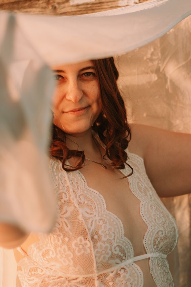 Intimate portrait through sheer fabric with warm golden lighting.