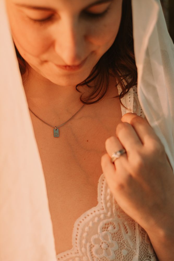Intimate portrait showing delicate necklace and lace detail in warm lighting.