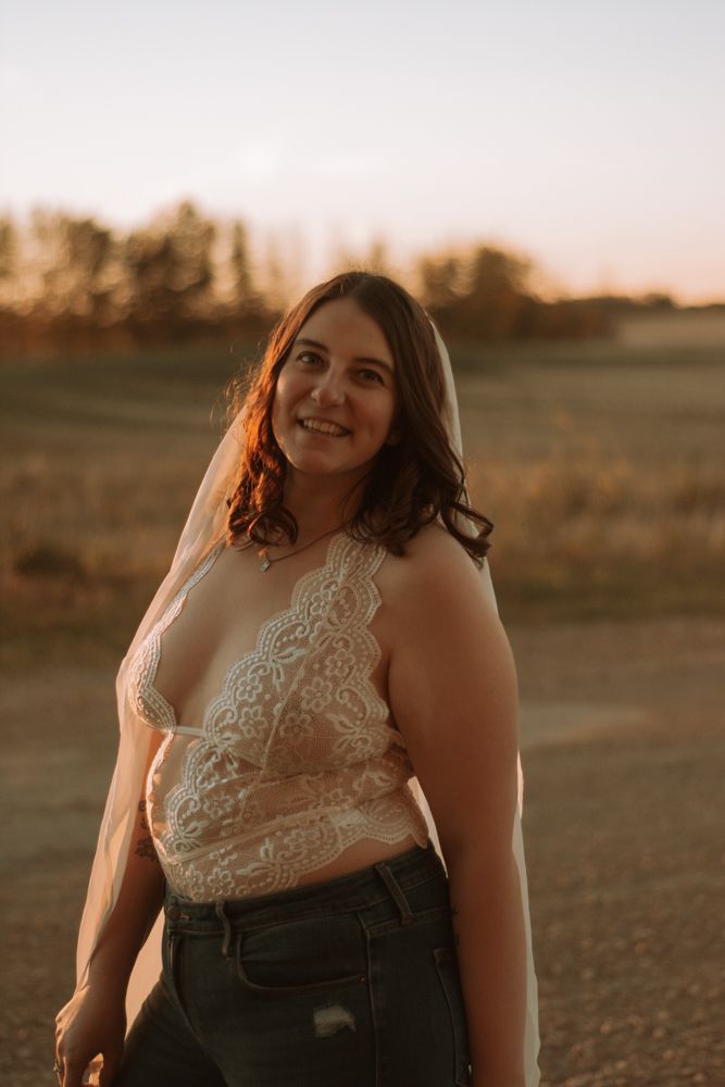 Portrait in a field during golden hour wearing a lace top and distressed denim.